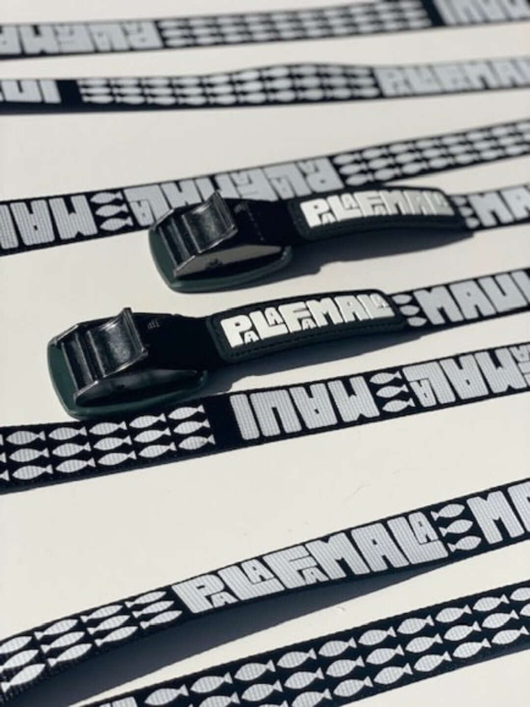 Black straps Palafamala branding on a white background