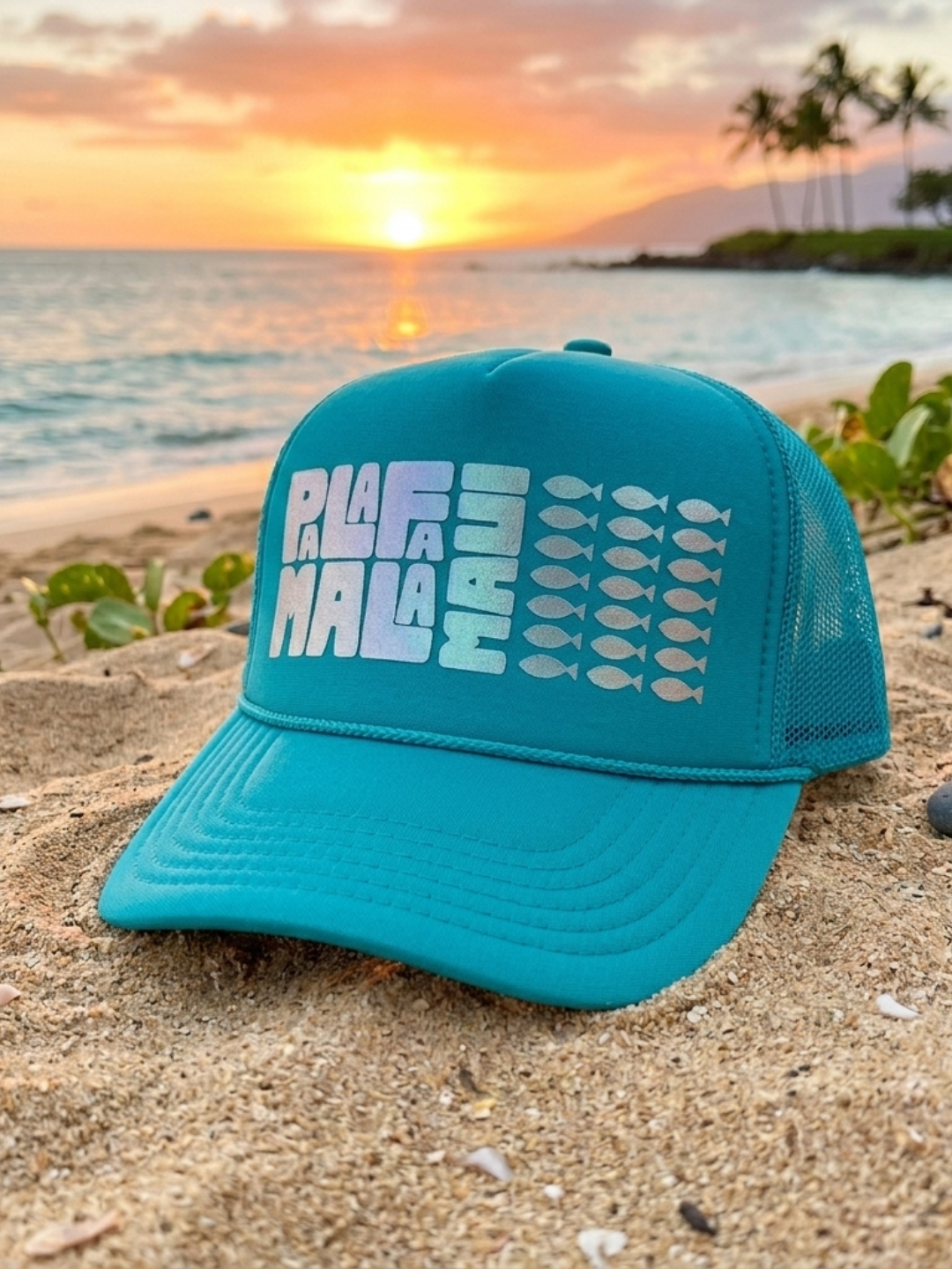 Turquoise cap with 'PALAFAMALA' text on a beach at sunset