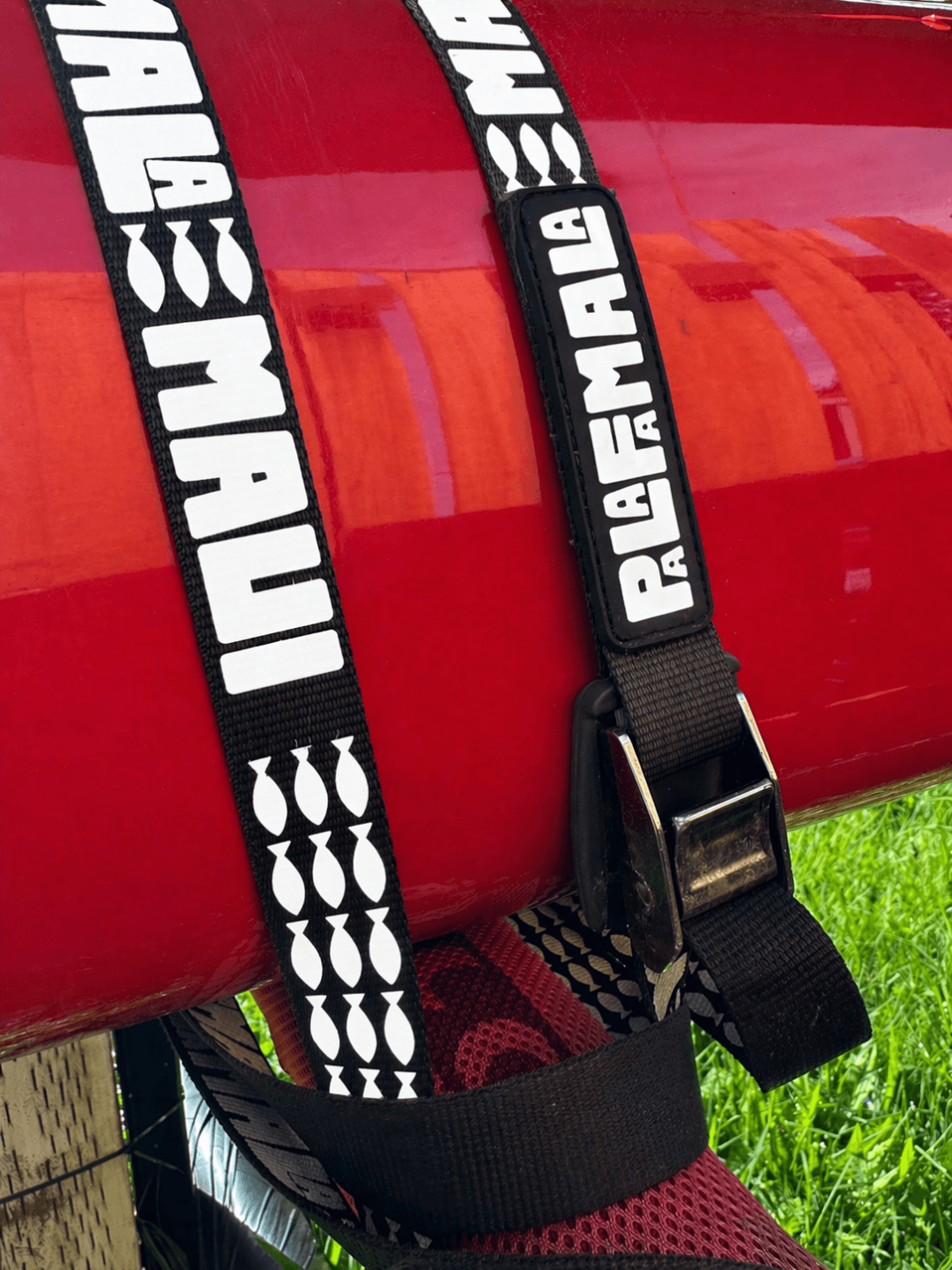 Black strap with white PALAFAMALA branding letters and graphics on a red kayak boat
